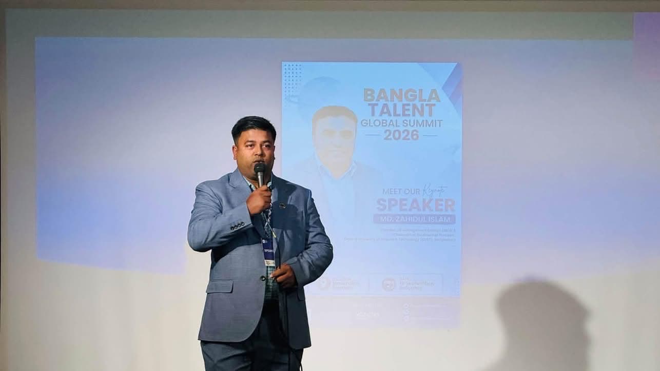 A speaker in a blue suit talks into a microphone in front of the summit screen