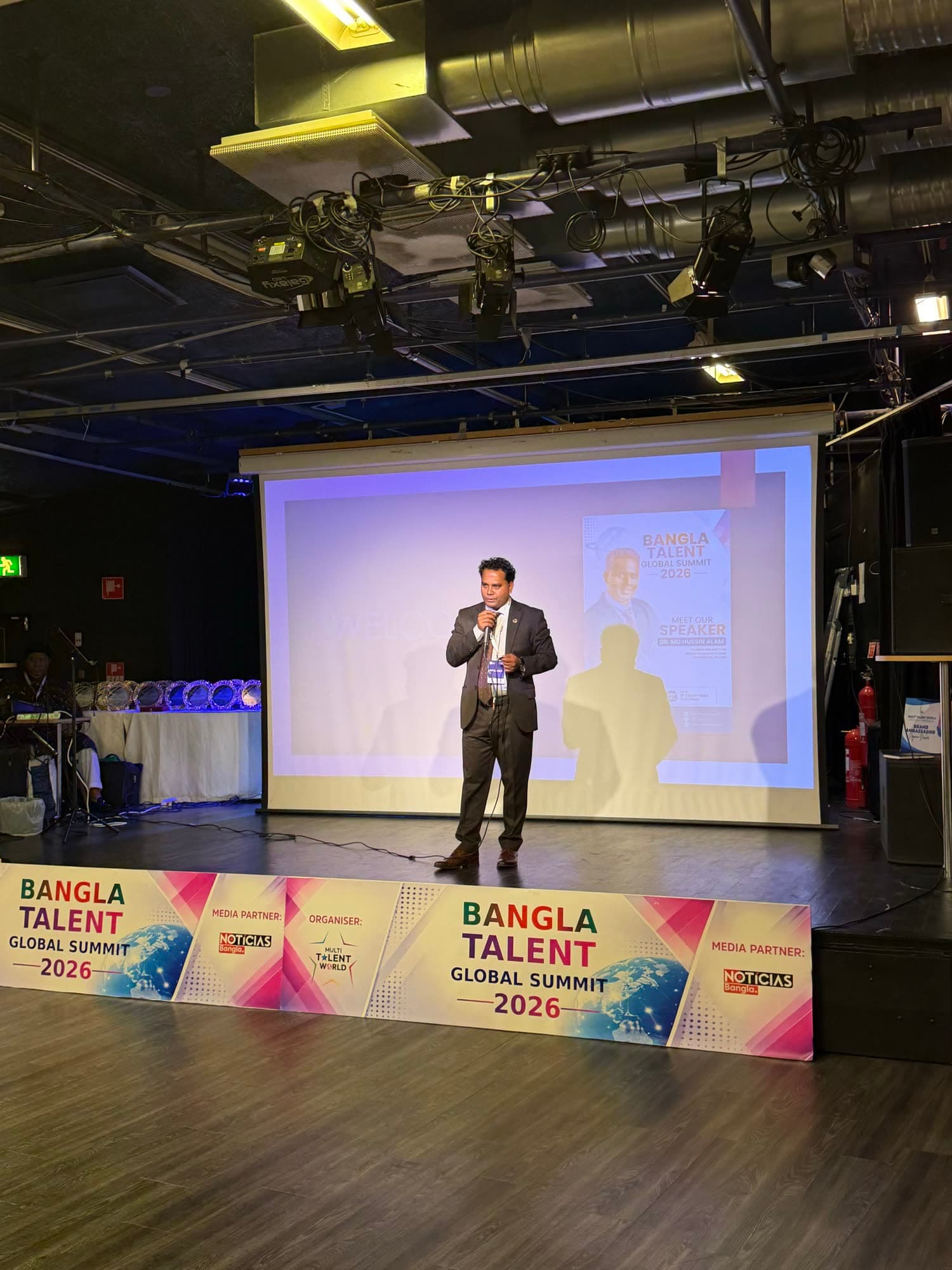A speaker alone on the summit stage, seen from the back of the hall